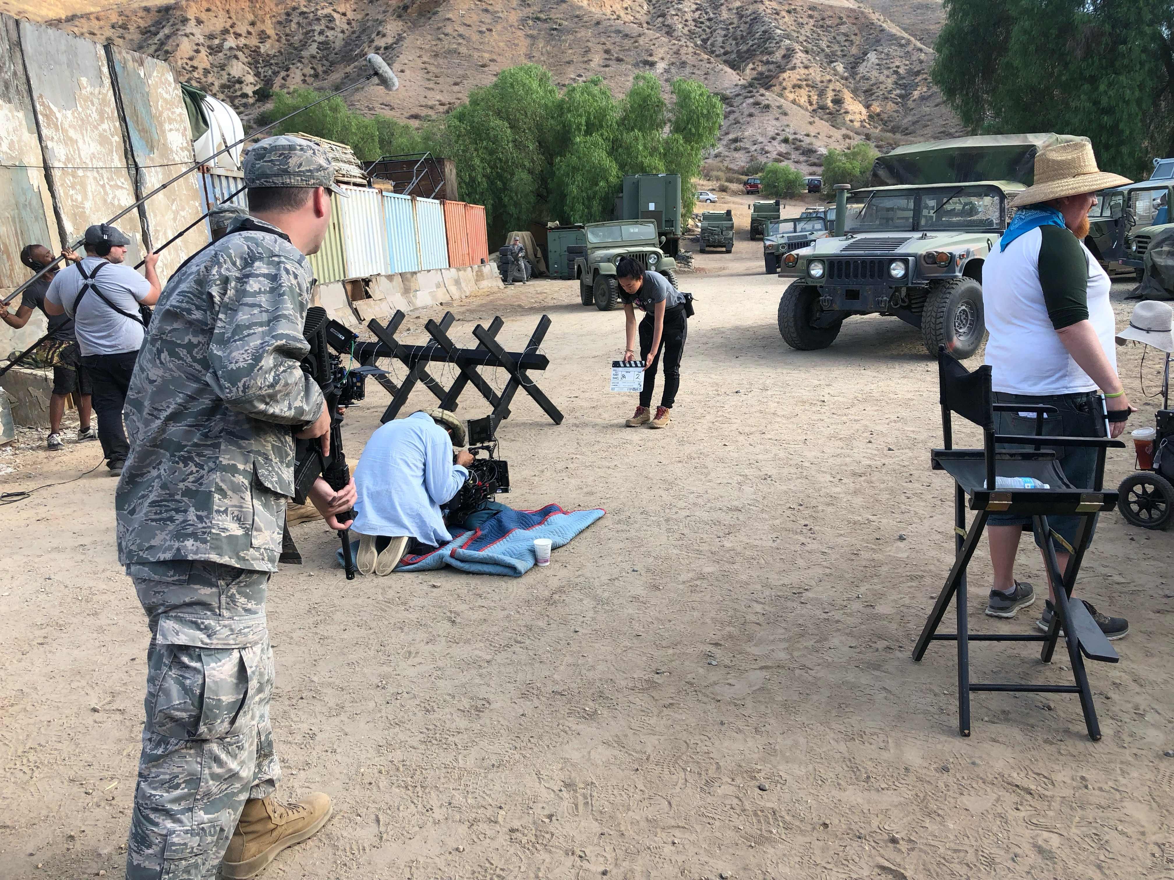 Behind the scenes on a military-themed film set with boom operators and a camera crew